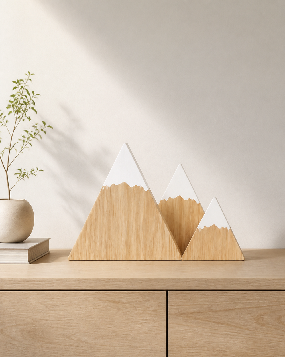 Dreiteilige Berg-Holzdeko in hellem Holzton auf einem Sideboard
